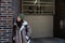 Young homeless girl or woman standing on the street. Evicted female leaning on the building wall, feeling miserable and sad after