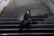 Young homeless man lost in depression sitting on ground street concrete stairs