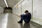 Young homeless man lost in depression sitting on ground street subway tunnel