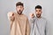 Young homosexual couple standing over white background pointing with finger surprised ahead, open mouth amazed expression,