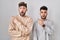 Young homosexual couple standing over white background surprised pointing with finger to the side, open mouth amazed expression