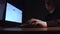 Young homosexual with vitiligo working in front of two computer screen. Dark night room.