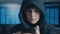 Young hooded hacker kid using a smartphone device to hijack. Genius boy wonder hacks system at cyberspace.