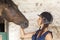 Young horsewoman with its horses in the stable