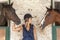 Young horsewoman with its horses in the stable