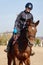 Young horsewoman riding on brown horse in paddok outdoors, copy space.