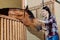 Young horsewoman standing in stable and petting dark horse