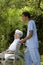 Young Hospital staff happily pushing a senior patient in wheelchair outdoors