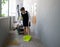 Young hotel maid cleaning floor with broom and dustpan. Housekeeping cart on the corridor in front of the hotel room. The laundry