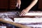 Young house wife preparing the homemade pasta at kitchen. Woman cutting long dough stripe for cooking pasta