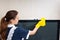 Young housekeeper dusting a television set