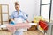 Young housekeeper woman ironing clothes at home looking positive and happy standing and smiling with a confident smile showing