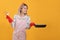 Young housewife with frying pan and martini on yellow background. Space for text