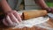 A young housewife kneads yeast dough on a wooden board.