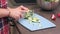 Young housewife slices cucumbers on plastic board