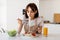 Young housewife tasting spaghetti and vegetable salad, enjoying delicious lunch at home, sitting in modern kitchen