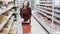 Young housewife with trolley shopping at the grocery store.