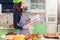 Young housewife trying to find a new recipe in cookbook while standing at table with food and ingredients