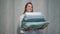 A young housewife woman holds a stack of fresh washed clean linen in her hands.