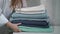 A young housewife woman takes a stack of fresh washed clean linen in her hands.