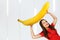 Young hunger pretty funny girl holds huge and large banana