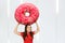 Young hunger pretty funny woman holds huge and large pink donut. Girl walks with big heavy cake