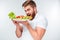 Young hungry bearded man eating salad