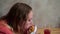 A young hungry girl eating a hamburger. Sitting at a table in a cafe. Slow mo