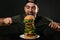 Young hungry man with cutlery eating huge burger