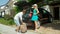 Young husband picks up the last suitcase to pack in the excited couple`s black car before setting off for their summer vacation.