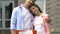 Young husband and wife near sold sign outside house smiling camera, relocation