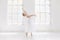 Young and incredibly beautiful ballerina is posing and dancing in a white studio