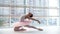 Young and incredibly beautiful ballerina is posing and dancing in a white studio full of light.
