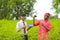 Young indian banker and farmer showing smartphone and card at green field