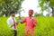 Young indian banker and farmer showing smartphone and card at green field