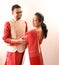 A young indian bengali assamese married couple dressed in red and white ethnic indian dress and smilinga young indian bengali