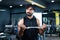 Young Indian bodybuilder busy doing biceps workout by lifting weight using barbells at gym - concept of musclebuilder