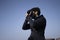 Young indian boy clicking photos from his DSLR camera with blue sky in the background