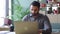 Young indian concentrated ceo sitting at desk using laptop in office.