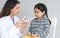 Young Indian dentist holding a jaw model and toothbrush, demonstrating right way to clean teeth and gums by brushing properly to