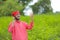 Young indian farmer talking on mobile phone at green pigeon field