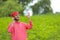 Young indian farmer talking on mobile phone at green pigeon field