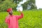 Young indian farmer talking on mobile phone at green pigeon field