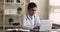 Young Indian general practitioner working on laptop in clinic office