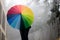 Young indian girl with a colorful umbrella standing on a foggy street in himachal pradesh