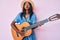 Young indian girl playing classical guitar puffing cheeks with funny face