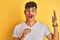 Young indian man holding fanny mustache standing over isolated yellow background very happy and excited, winner expression