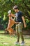 Young indian man playing with boxer dog on green lawn in public park, jumping dog catch training