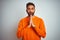 Young indian man wearing orange sweater over isolated white background praying with hands together asking for forgiveness smiling