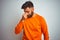 Young indian man wearing orange sweater over isolated white background tired rubbing nose and eyes feeling fatigue and headache